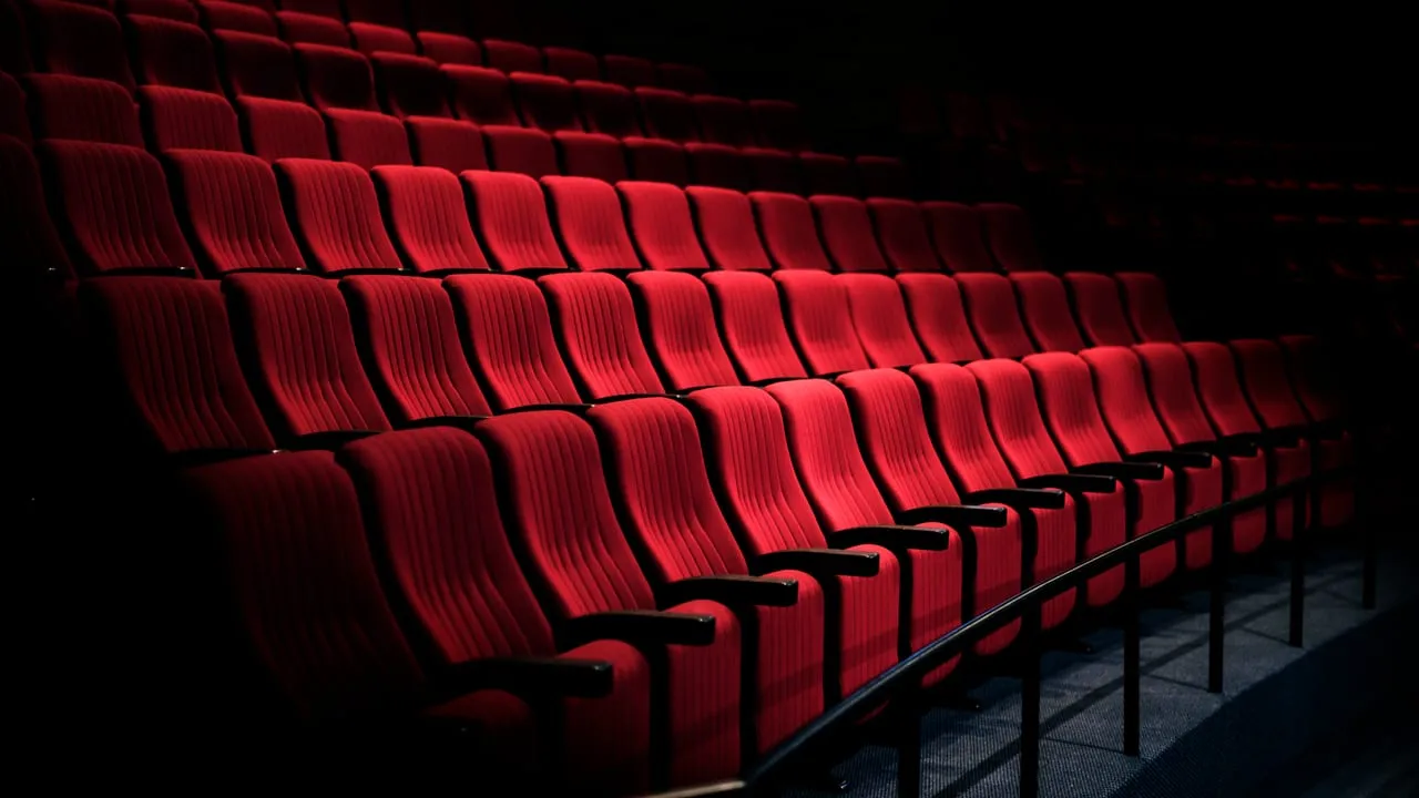 Fileiras de poltronas vermelhas de sala de cinema